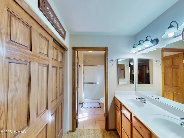 bathroom featuring tile patterned flooring, double vanity, a shower, and a sink