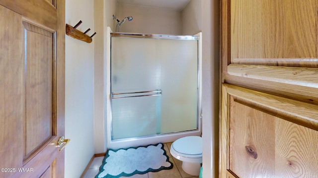 bathroom featuring tile patterned flooring, toilet, and a shower with door