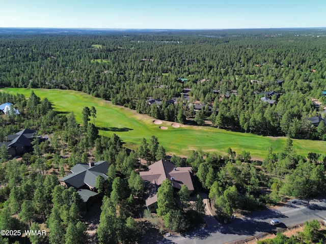 drone / aerial view featuring view of golf course and a wooded view