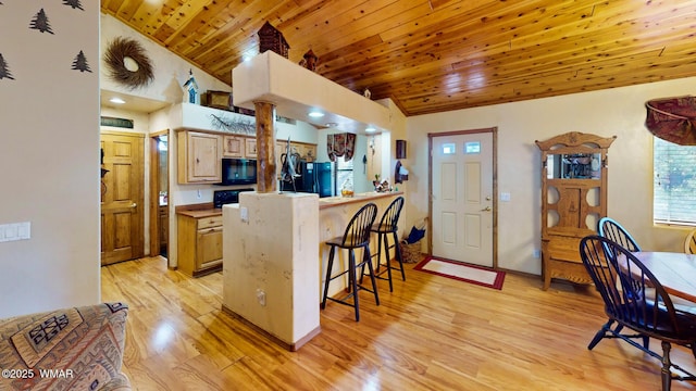 kitchen featuring a peninsula, black appliances, a kitchen bar, wooden ceiling, and light wood-type flooring