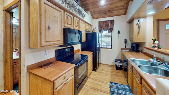 kitchen featuring lofted ceiling, a sink, black appliances, wood counters, and light wood-type flooring