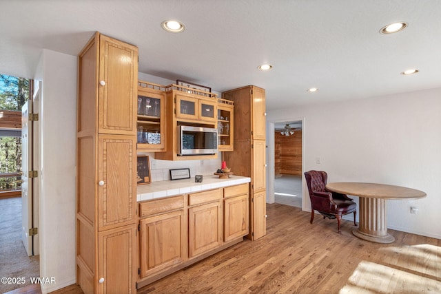 1825 E Woodchuck Ln, Pinetop, AZ 85935 - kitchen with tile countertops, recessed lighting, light wood-type flooring, stainless steel microwave, and glass insert cabinets