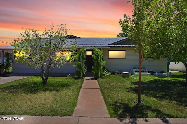 view of front of home featuring metal roof and a lawn