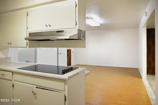 kitchen featuring light countertops, light wood-style flooring, black electric cooktop, and under cabinet range hood