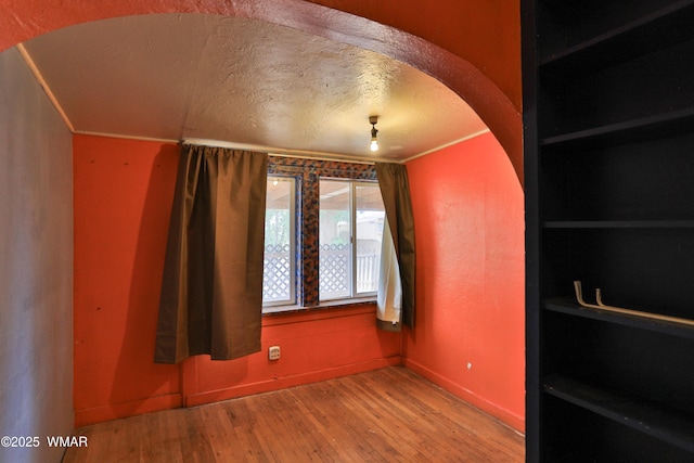 219 W Elm St, Winslow, AZ 86047 - empty room with wood finished floors, a textured ceiling, and arched walkways