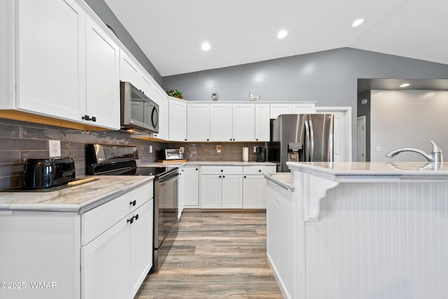 289 N Divot Dr, Eagar, AZ 85925 - kitchen featuring stainless steel appliances, lofted ceiling, light wood-style flooring, white cabinetry, and a kitchen bar