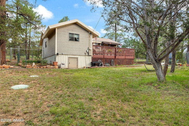 back of property with a deck, a yard, and fence