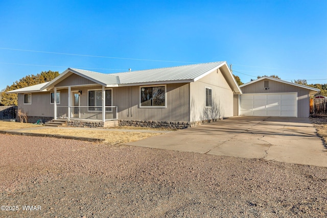 ranch-style home featuring a garage, an outbuilding, covered porch, and metal roof