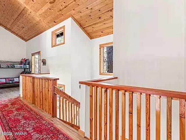 hall with lofted ceiling, wooden ceiling, wood finished floors, and an upstairs landing