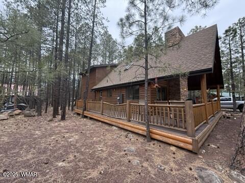 back of property featuring a chimney and a shingled roof
