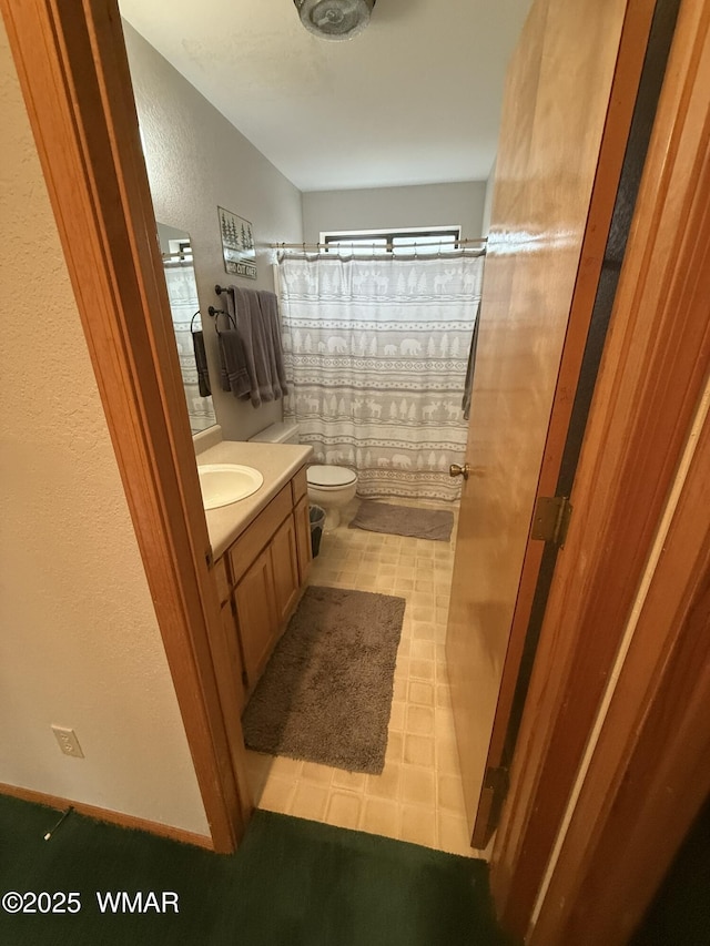 full bath with a textured wall, vanity, toilet, and a shower with curtain