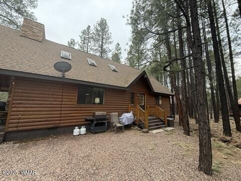 rear view of property featuring a shingled roof