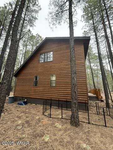view of side of property with fence and log veneer siding