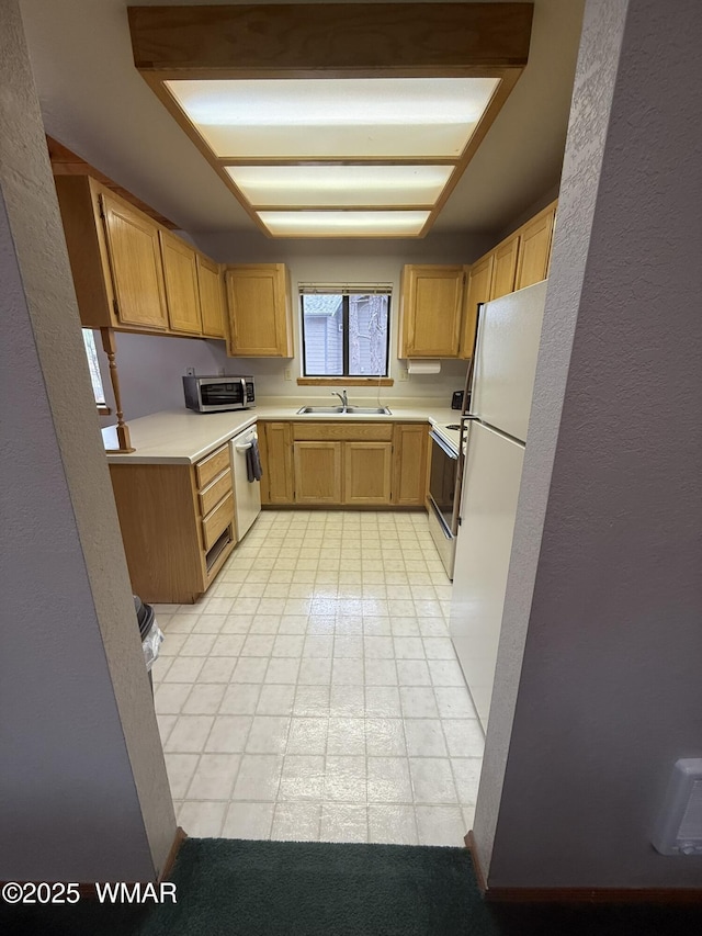 kitchen featuring light tile patterned flooring, white appliances, light countertops, and a sink