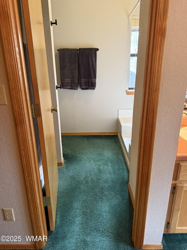bathroom with baseboards, a washtub, carpet flooring, and a textured wall