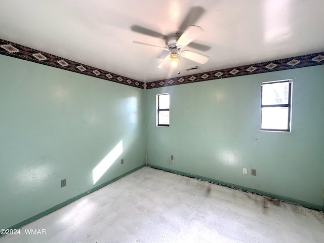spare room with ceiling fan, visible vents, and baseboards