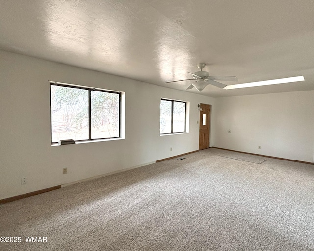 carpeted empty room featuring a ceiling fan, baseboards, and a textured ceiling