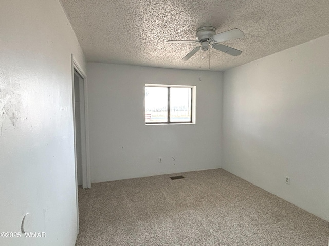 spare room with a ceiling fan, carpet, visible vents, and a textured ceiling