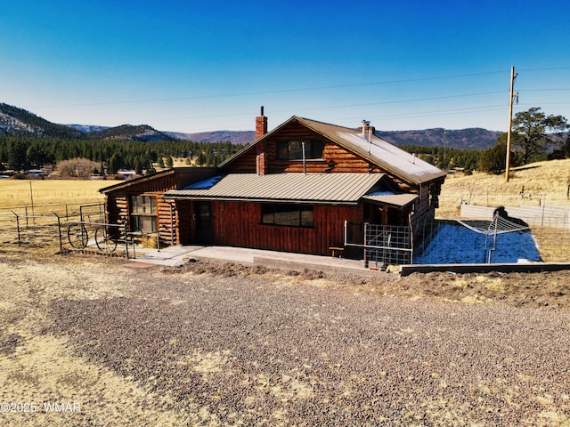 exterior space with metal roof, a chimney, an exterior structure, and a mountain view