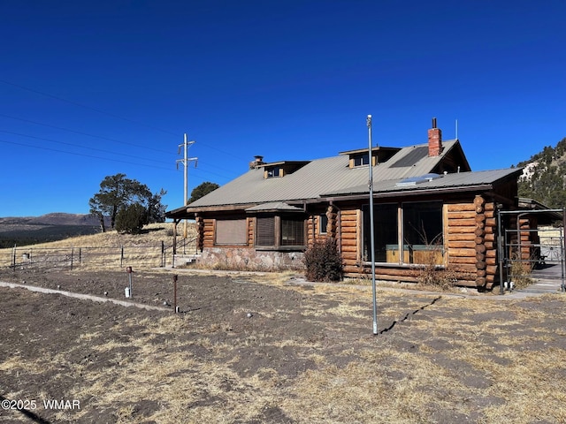 view of front of property featuring a chimney, metal roof, and log exterior