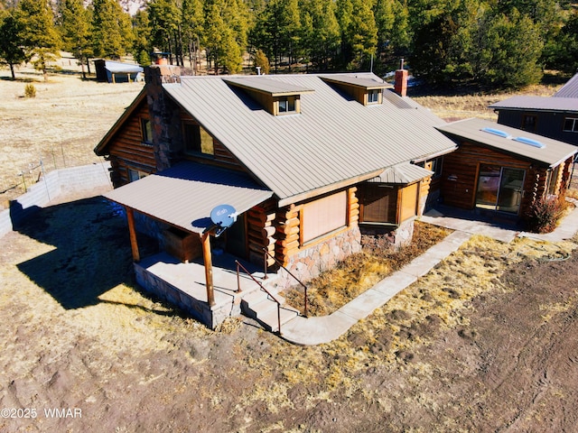 view of front of property featuring a chimney, metal roof, and log exterior