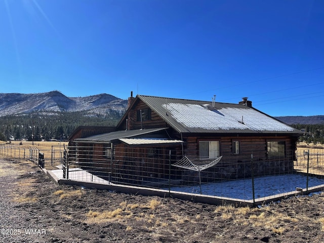 back of house with metal roof, a mountain view, and a chimney