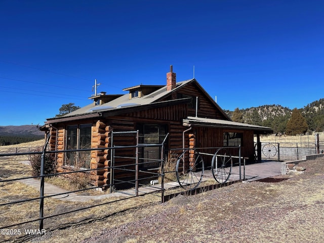 exterior space with an outbuilding, log exterior, a chimney, and an exterior structure