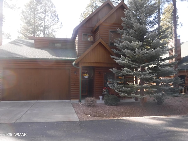 exterior space with concrete driveway, log veneer siding, and an attached garage