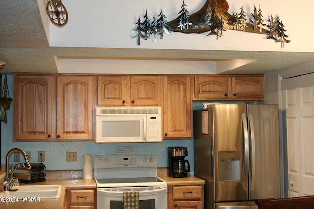 kitchen with light countertops, brown cabinetry, a sink, a textured ceiling, and white appliances