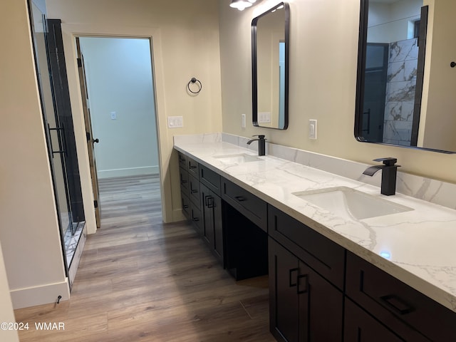 bathroom featuring double vanity, a sink, baseboards, and wood finished floors