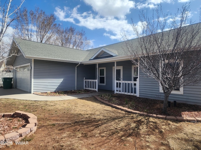 ranch-style house featuring covered porch, a shingled roof, and an attached garage