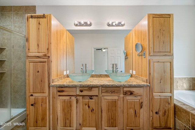 full bathroom featuring double vanity, tiled tub, a tile shower, and a sink