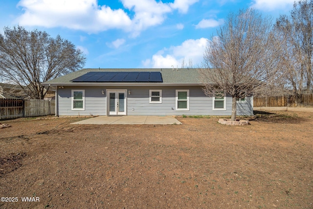 rear view of property with french doors, a patio, solar panels, a lawn, and fence