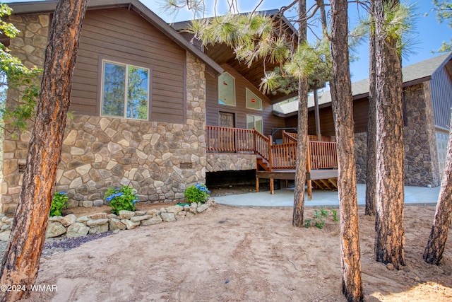 view of property exterior featuring stone siding and a wooden deck