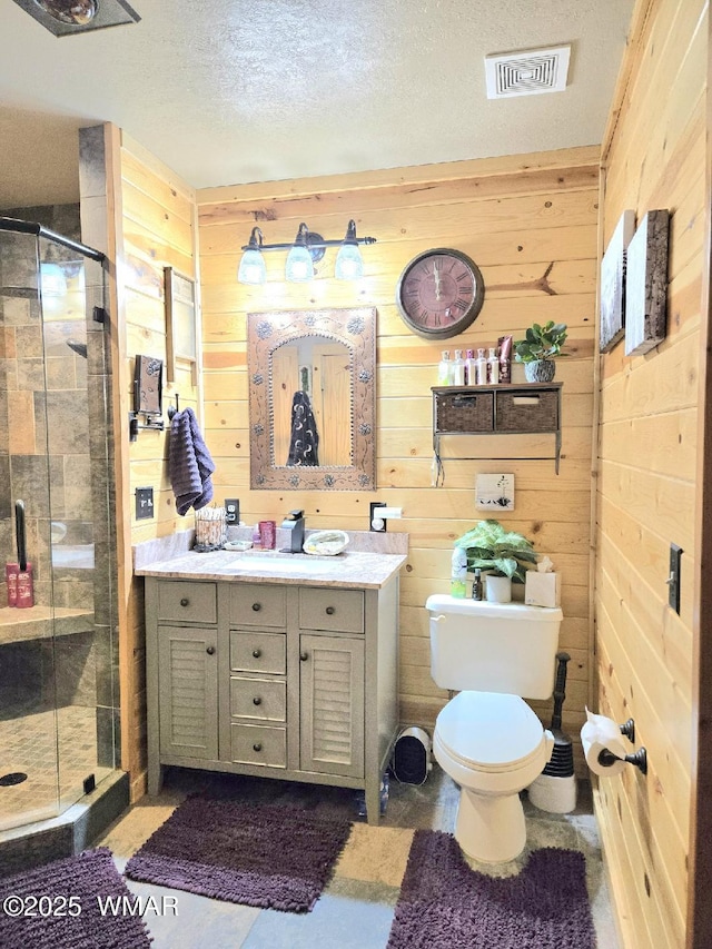 full bathroom featuring a textured ceiling, visible vents, a shower stall, wooden walls, and vanity