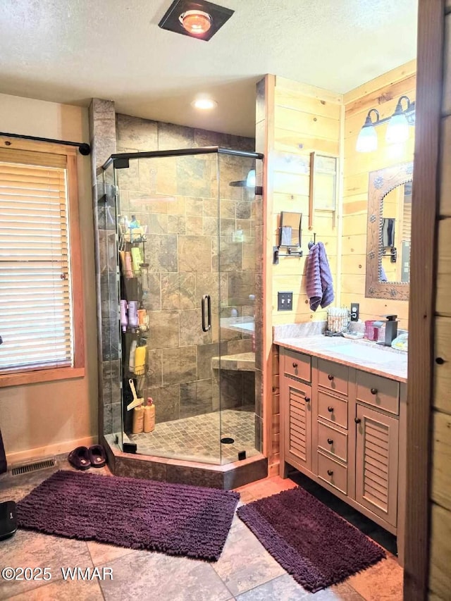 bathroom with a stall shower, vanity, and a textured ceiling