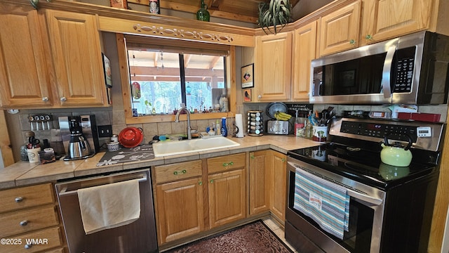 kitchen featuring appliances with stainless steel finishes, tasteful backsplash, tile countertops, and a sink