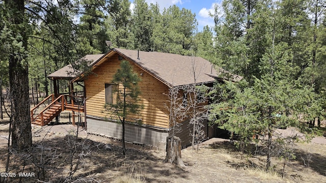 view of home's exterior featuring stairs and a shingled roof