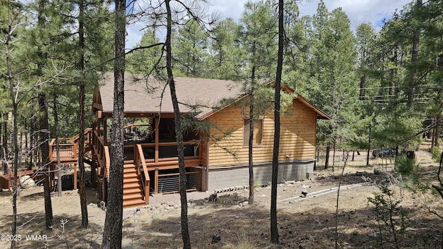 exterior space featuring a shingled roof, stairway, and a deck