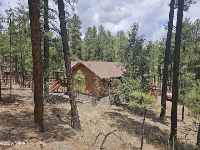 view of side of home featuring stairway and roof with shingles