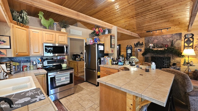 kitchen with a peninsula, light brown cabinets, appliances with stainless steel finishes, wood ceiling, and vaulted ceiling with beams