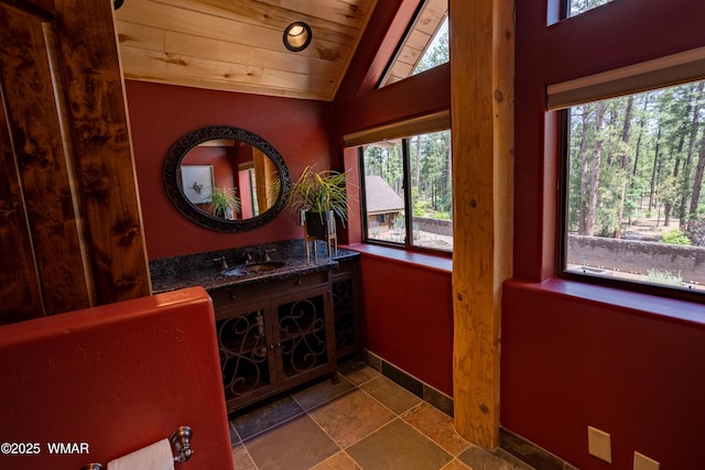 interior space with wood ceiling, stone finish floor, a sink, vaulted ceiling, and baseboards