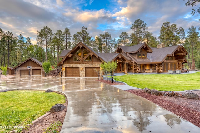 log cabin with a garage, concrete driveway, stone siding, log siding, and a front lawn