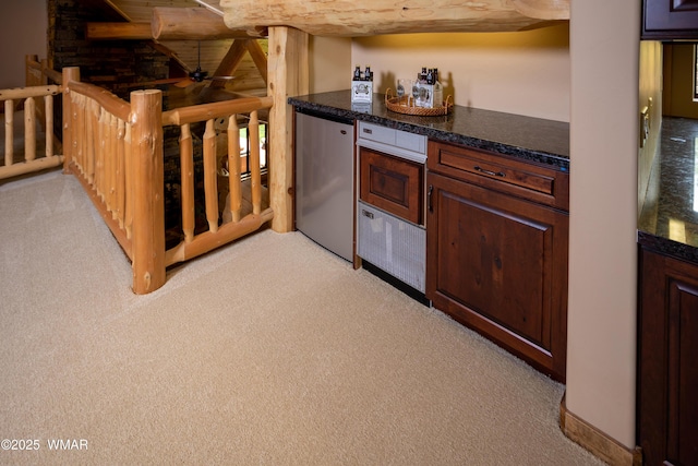 kitchen featuring light carpet, dark countertops, a ceiling fan, and refrigerator