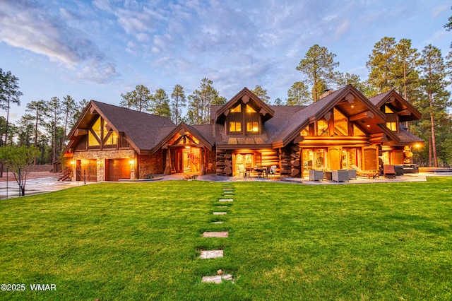 log-style house featuring a garage, stone siding, a front lawn, and an outdoor hangout area