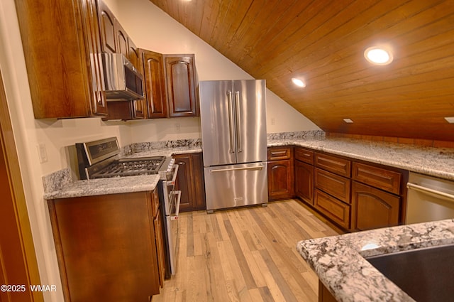 kitchen with lofted ceiling, light stone counters, stainless steel appliances, light wood-style floors, and recessed lighting