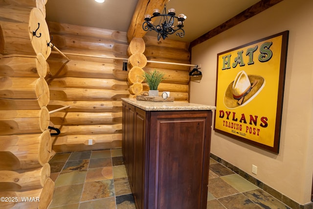 wine room featuring stone tile floors, baseboards, and a notable chandelier