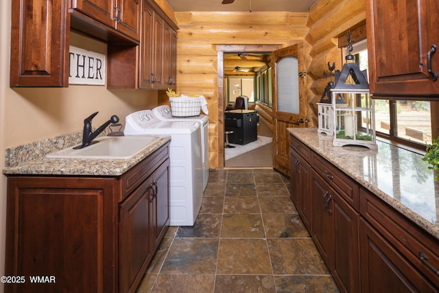 laundry room with a sink, a ceiling fan, washer and dryer, cabinet space, and stone tile flooring