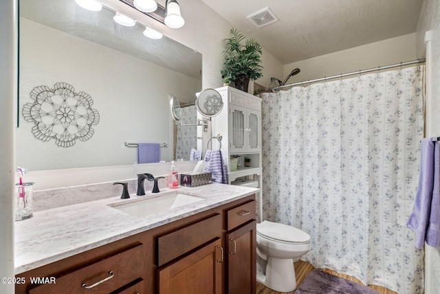 full bathroom featuring toilet, visible vents, a textured ceiling, and vanity