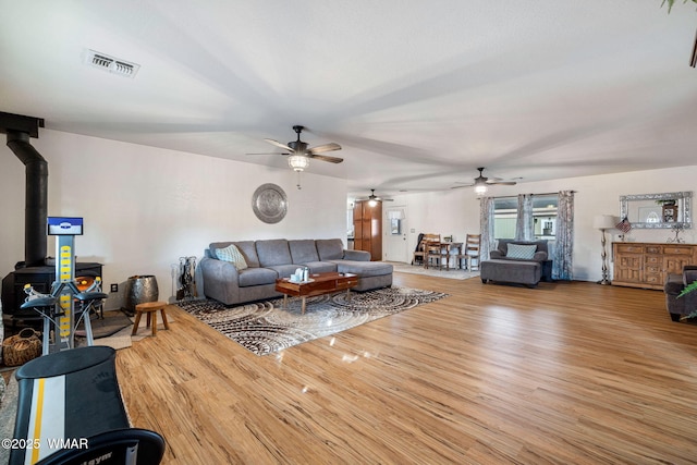 living area featuring visible vents, wood finished floors, and a wood stove